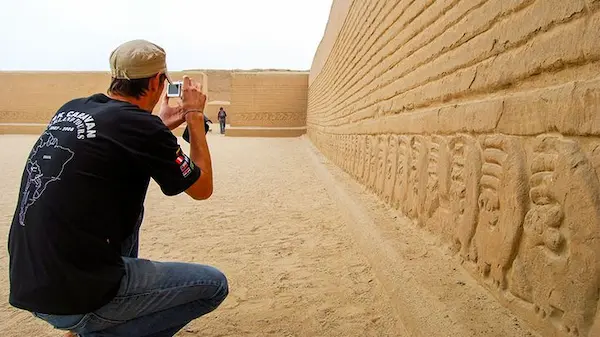 Imagen de una persona tomando foto a la ciudadela de Chan Chan,uno de los lugares turísticos del norte