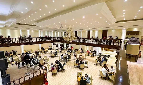 Interior rústico de Café Colonial con música en vivo y mesas de madera para clientes.