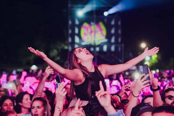 Fan disfrutando un concierto de cumbia con los brazos abiertos